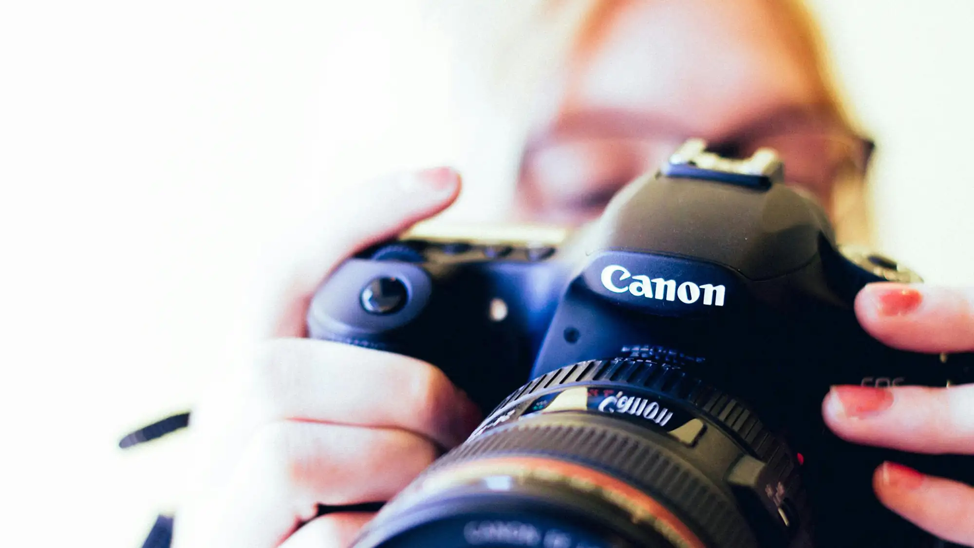 blonde woman looking a dslr camera she is holding