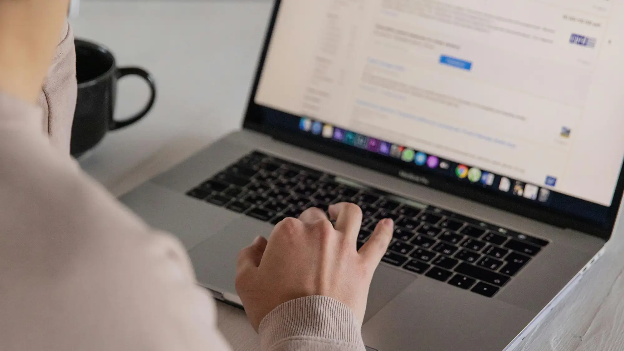 a person viewed, over their shoulder from behind, operating a laptop trackpad with their finger