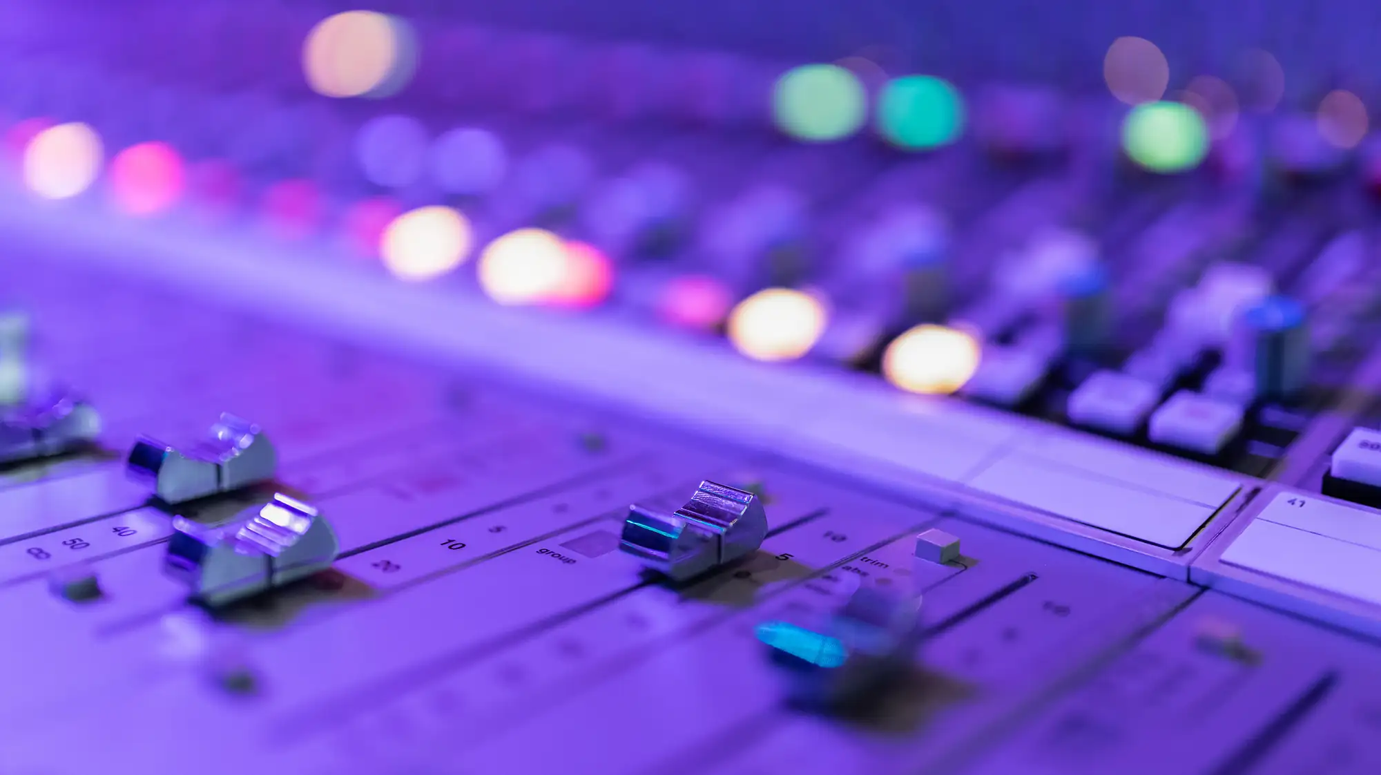 A sound board fader in purple lighting